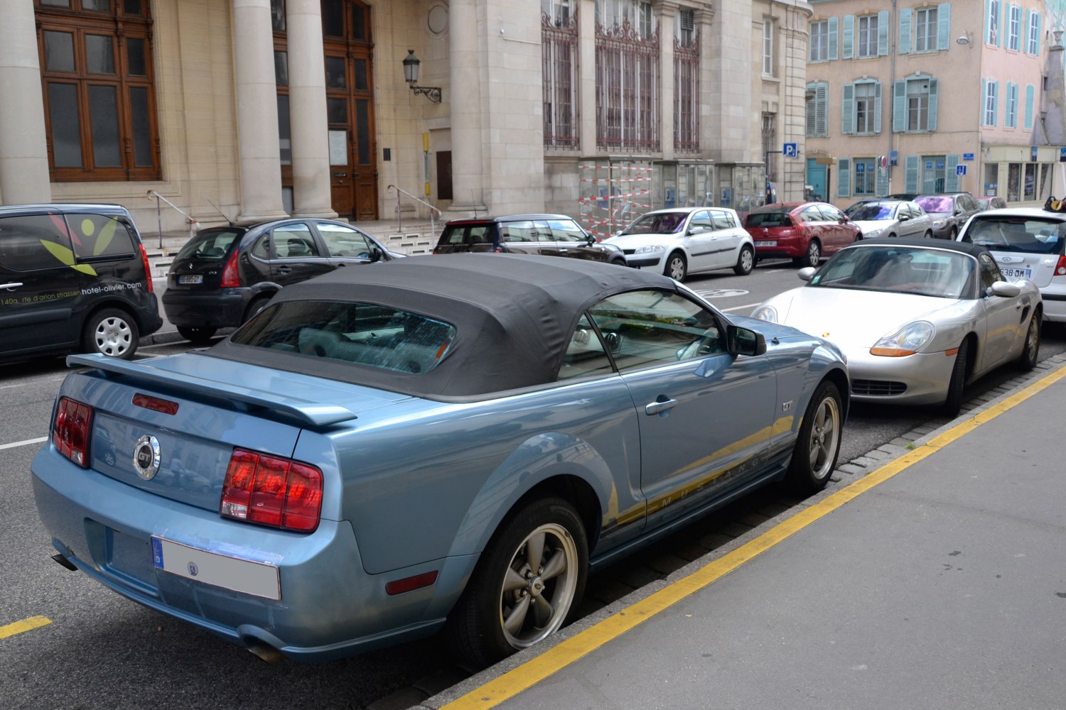 Convertible Mustang with closed soft top roof and rear spoiler.