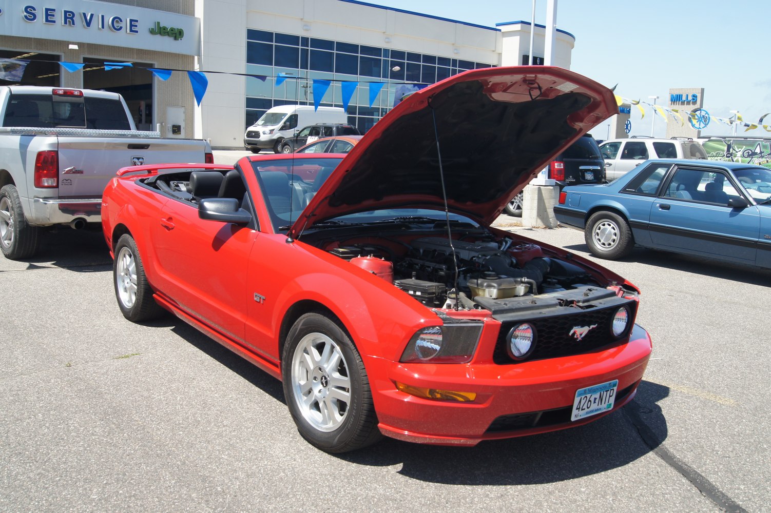Red convertible Mustang GT with open hood showing engine