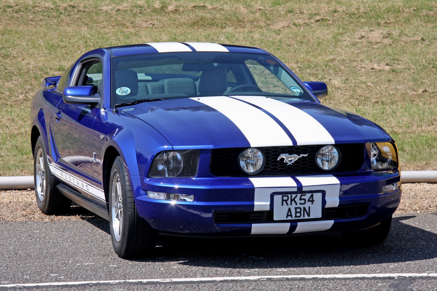 Front view of blue Mustang with white racing stripes and round headlights