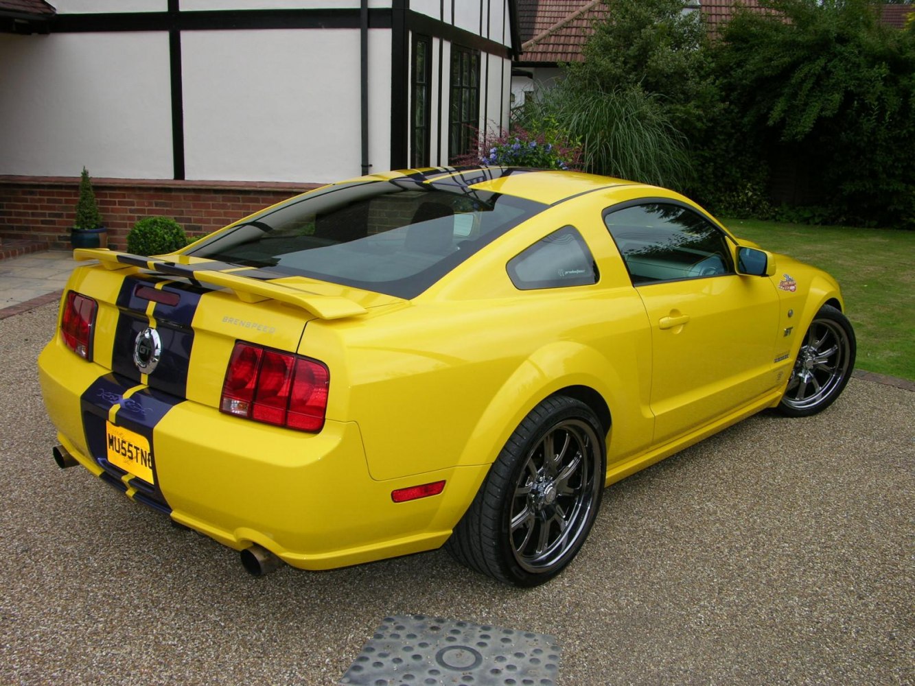 Yellow sports coupe with black racing stripes and rear spoiler