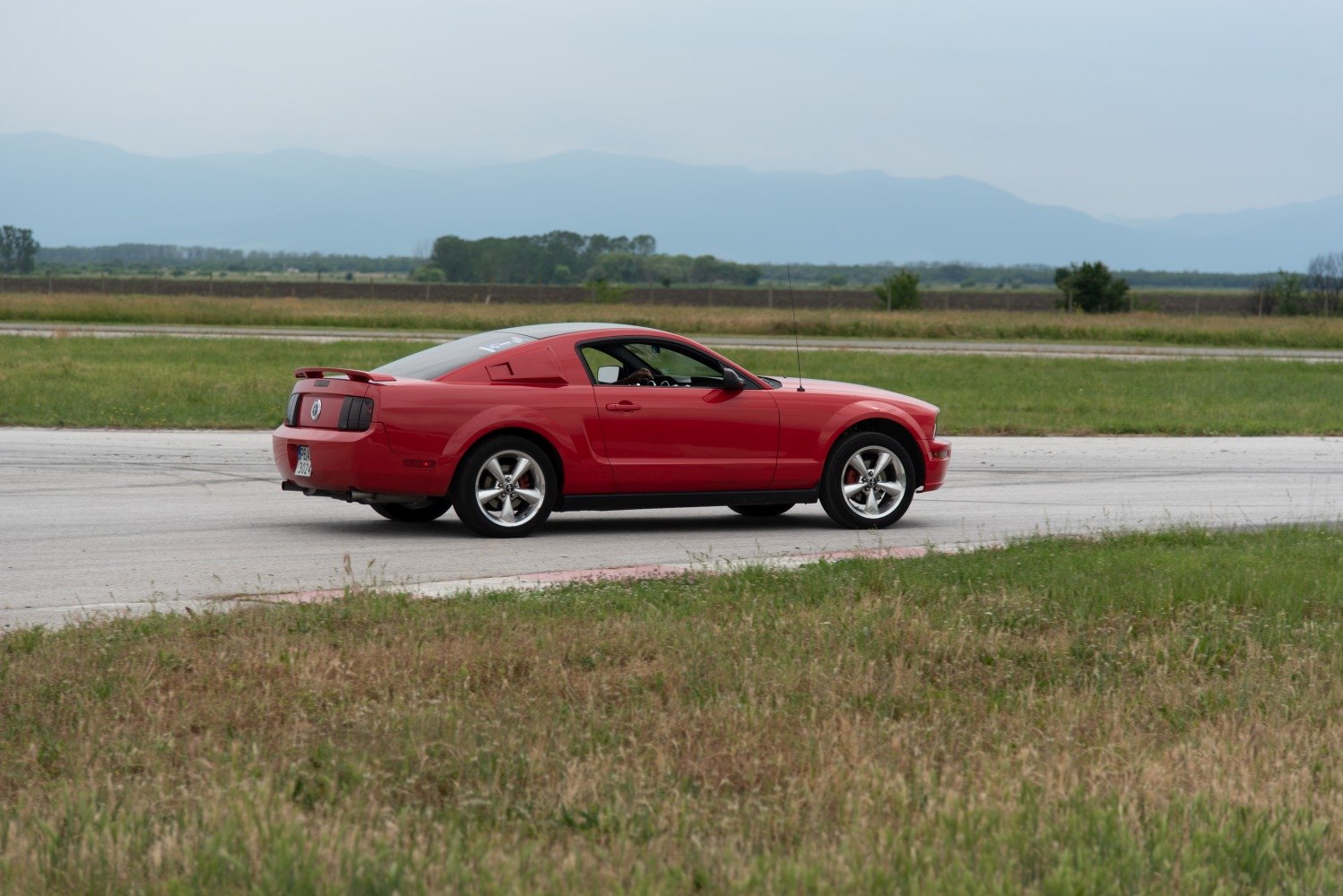 Red coupe with rear spoiler and five-spoke alloy wheels in side profile