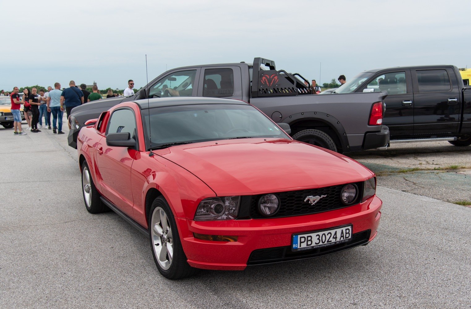 Red coupe with front grille, round headlights, and Mustang emblem
