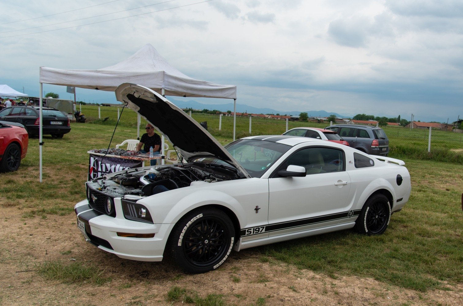 White sports coupe with open hood and custom black wheels
