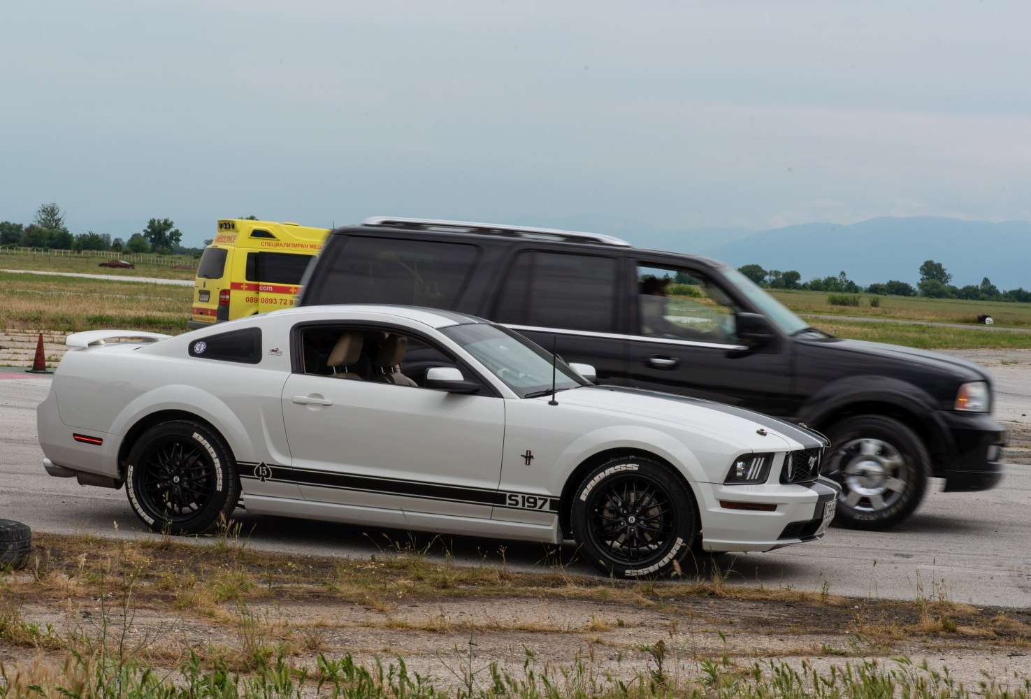 White sports coupe with black racing stripes and sporty wheels