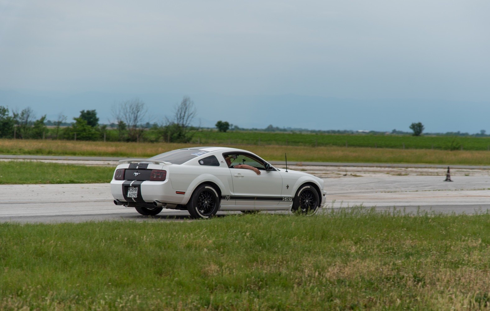 White coupe with black racing stripes rear side view