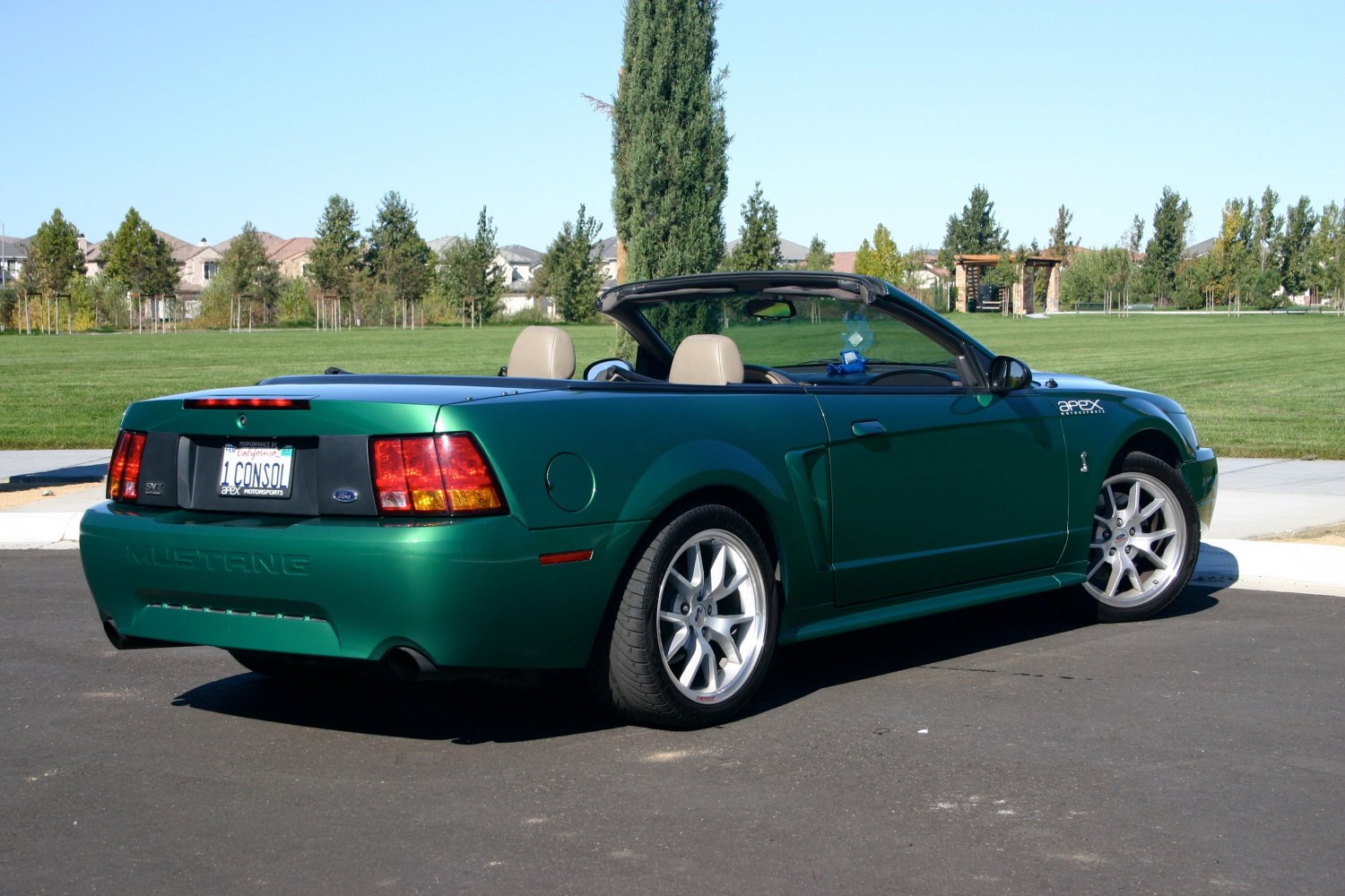Rear and side view of a green convertible with alloy wheels and open roof