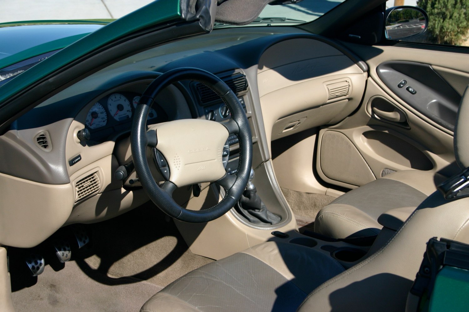 Dashboard and steering wheel interior with beige leather seats and manual transmission