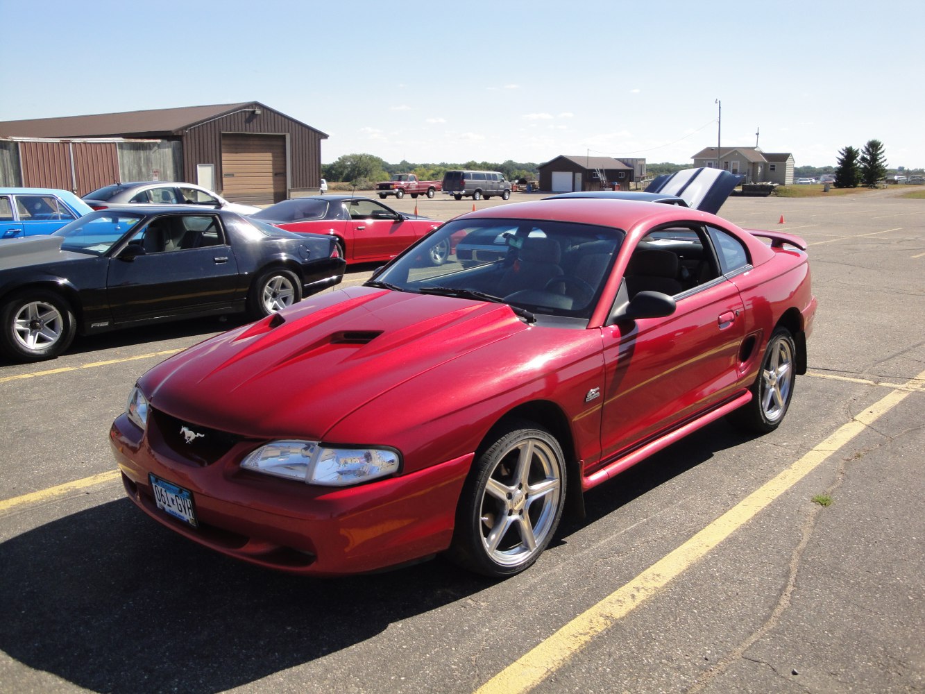 Red sporty coupe with hood scoops, side vents, spoiler, and chrome wheels