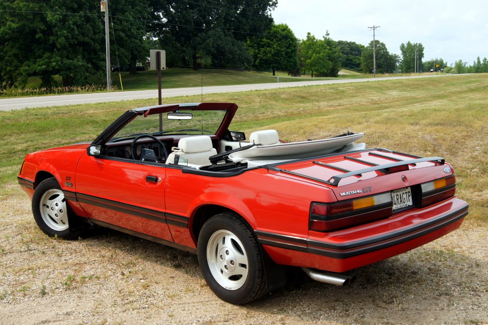 Red convertible with rear luggage rack and white interior seating.