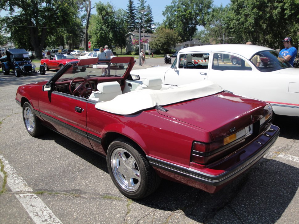 Red vintage convertible with white interior and soft top cover.