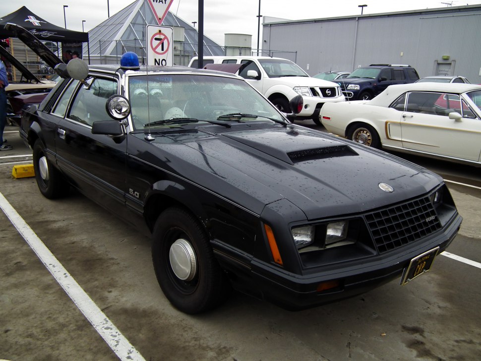 Black muscle car with hood scoop and police-style spotlight
