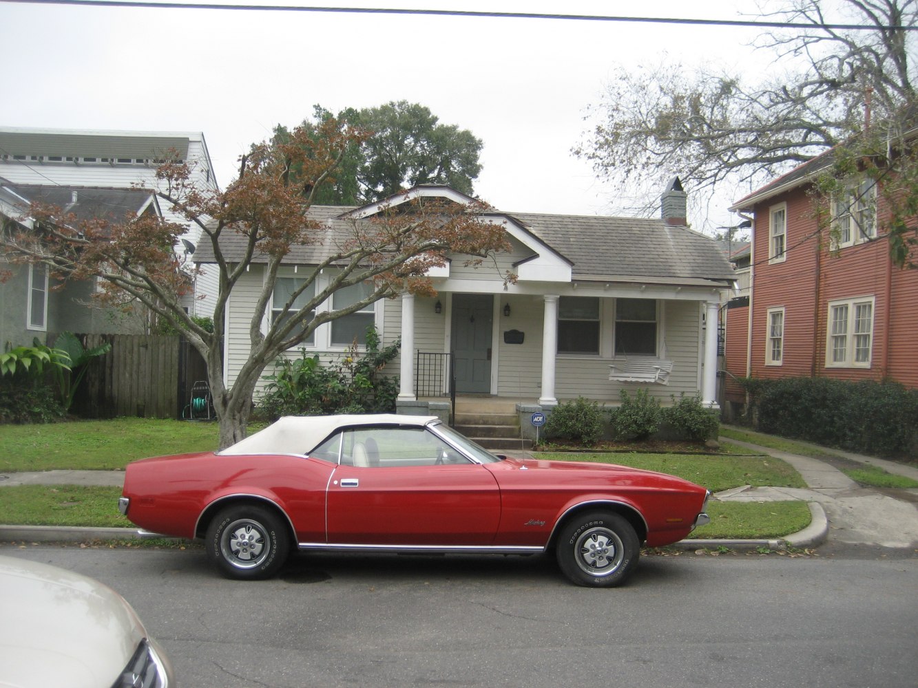 Red classic convertible with white soft top and distinctive long hood