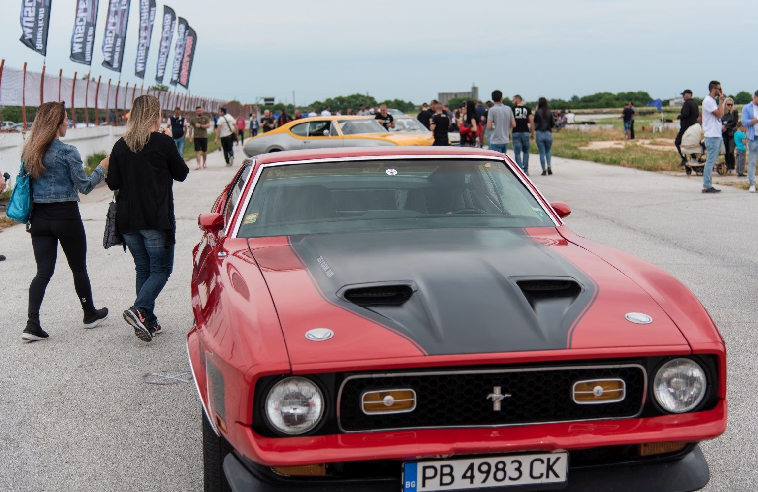 Front view of red muscle car with black hood vents and iconic grille.