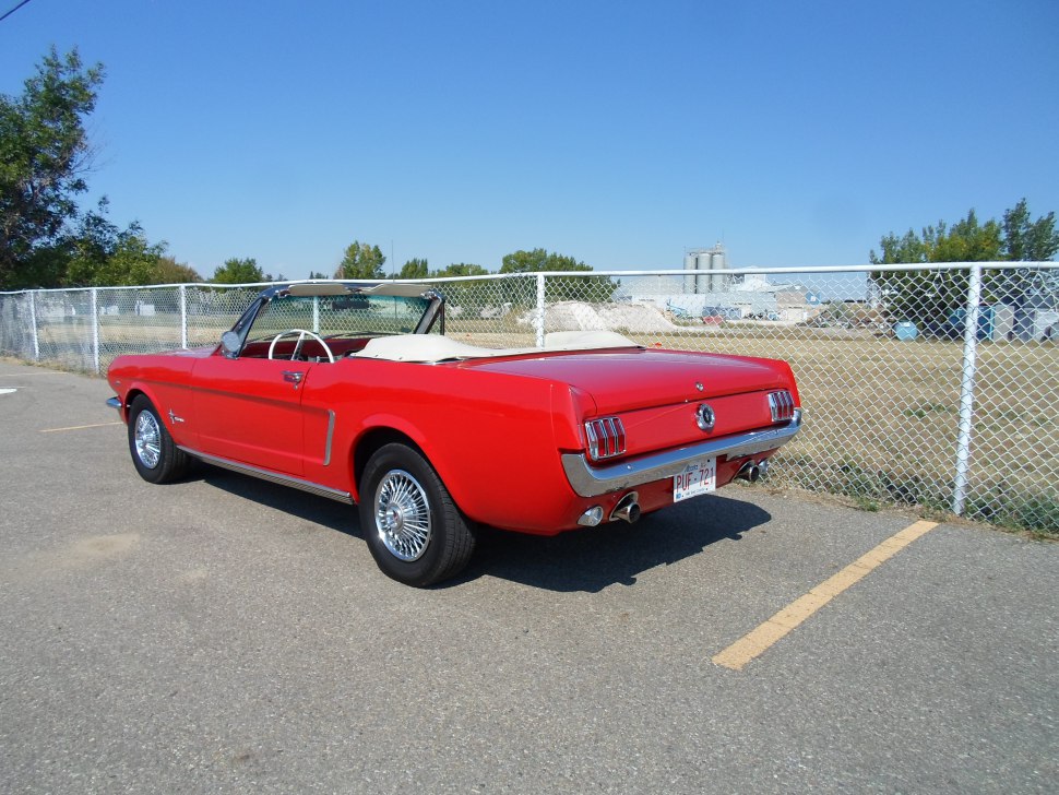 Rear-angle view of a red convertible with vintage taillights and wire-spoke wheels