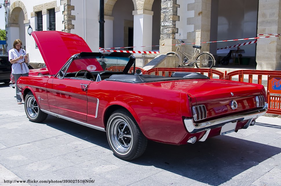 Red classic convertible Mustang with open hood and vintage design.