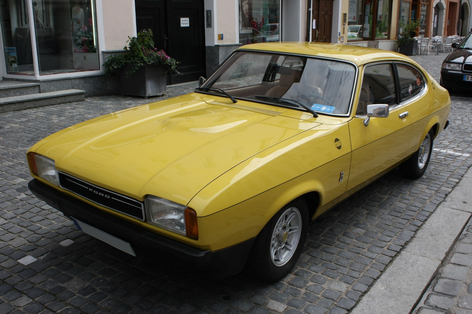 Yellow vintage sports coupe with alloy wheels and sleek aerodynamic design.