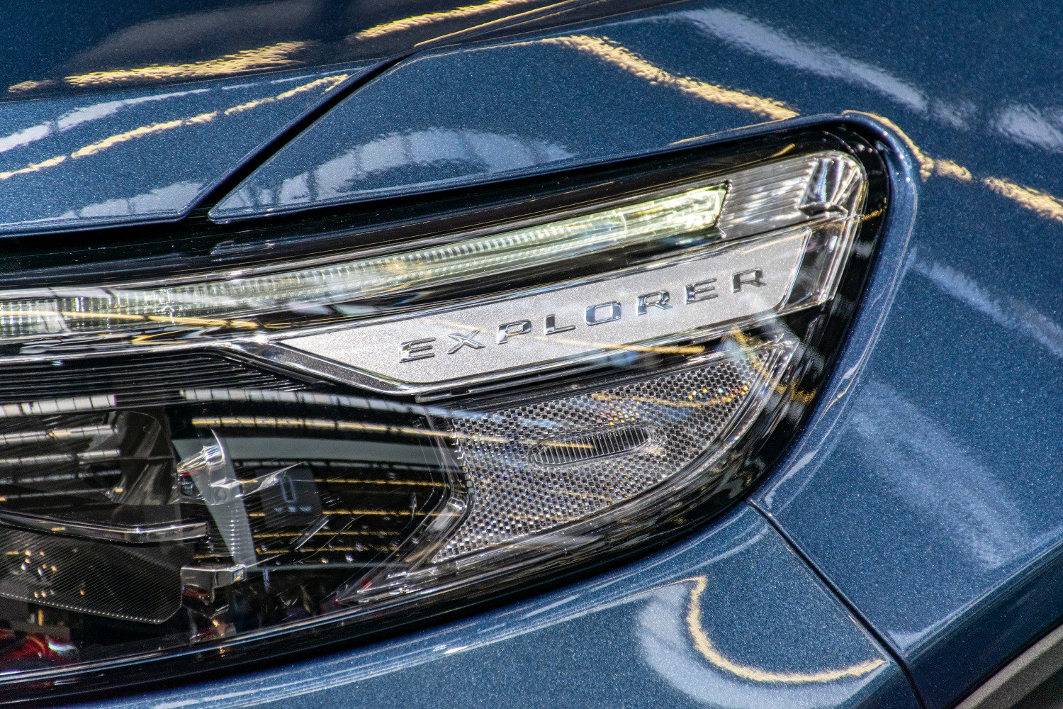Close-up of SUV headlight with illuminated Explorer badge