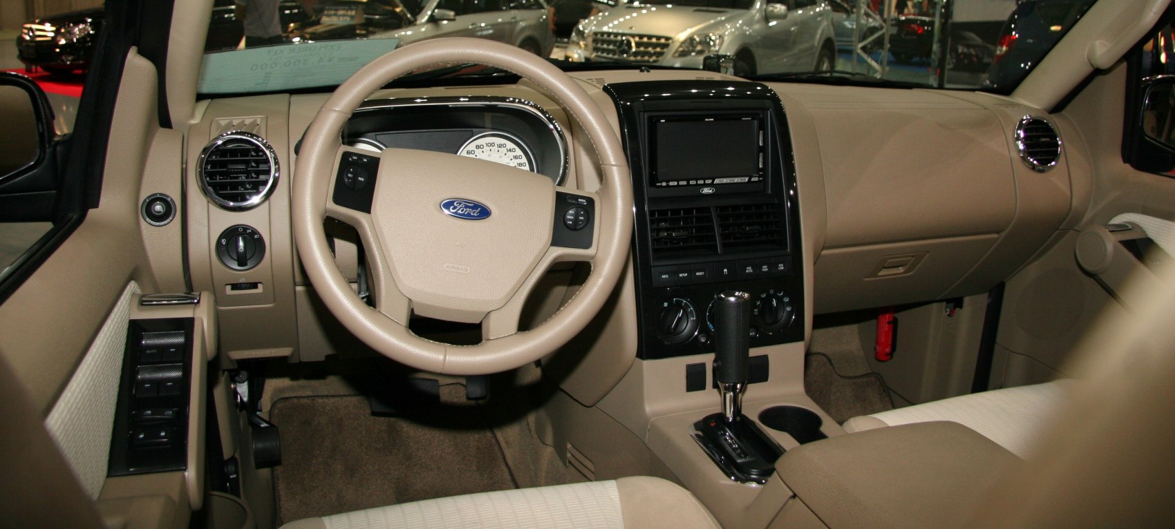 Beige dashboard and steering wheel with controls, automatic gearshift lever.