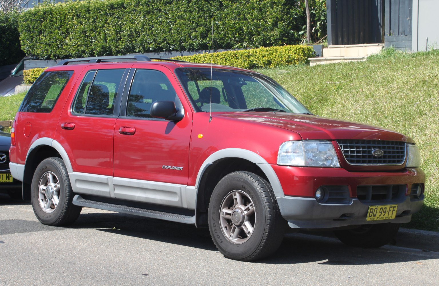 Red mid-size SUV with front-side view, roof rails, and prominent side fender flares