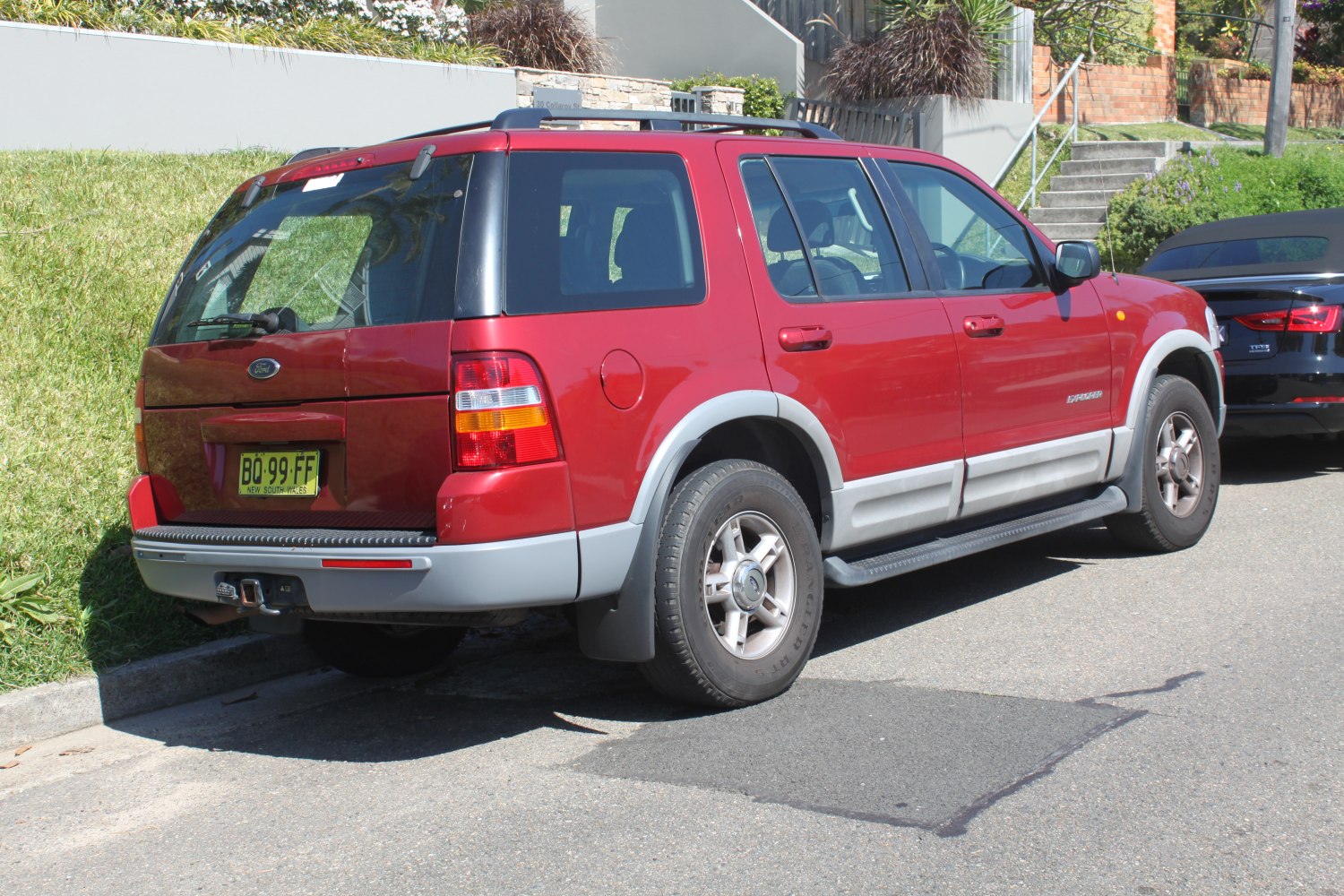 Red SUV rear-side view with grey cladding and roof rails