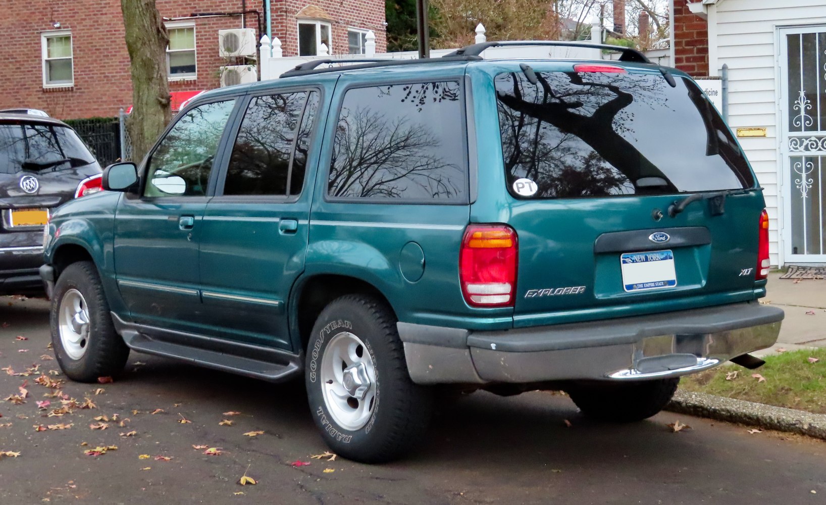Rear side view with tinted windows, roof rails, and prominent taillights.