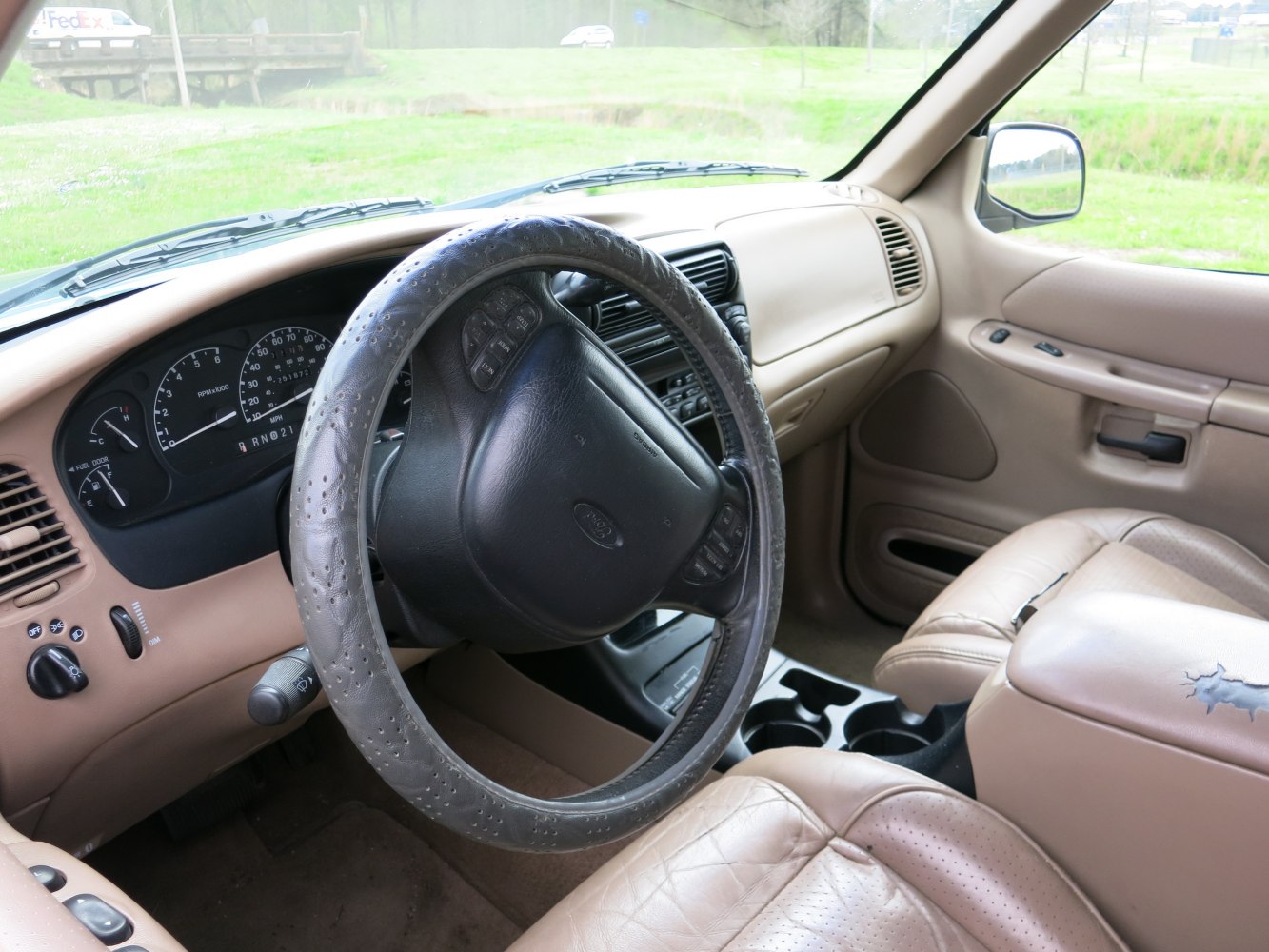Dashboard, steering wheel with controls, and tan leather seats in vehicle interior