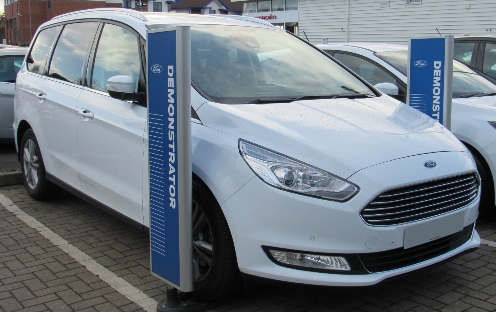 White MPV with sleek headlights and horizontal grille bars
