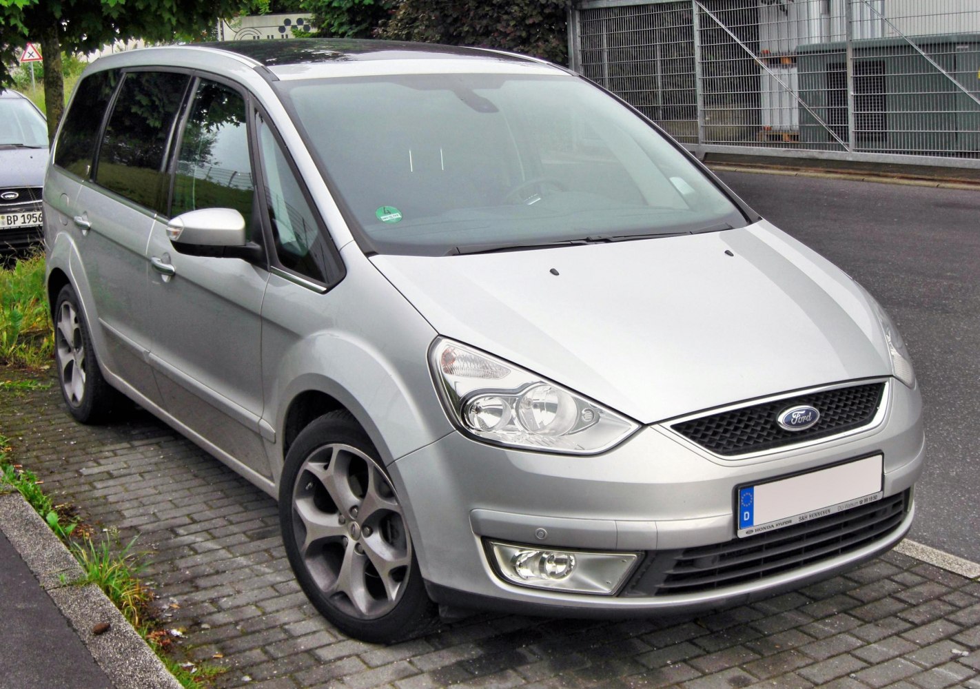 Silver MPV front-side view with distinctive headlights and alloy wheels parked on street