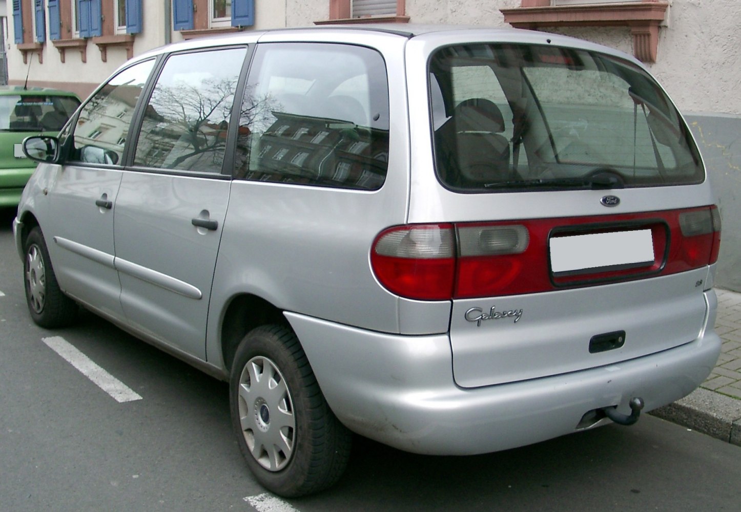 Silver minivan rear with unique tail light and a tow hitch.