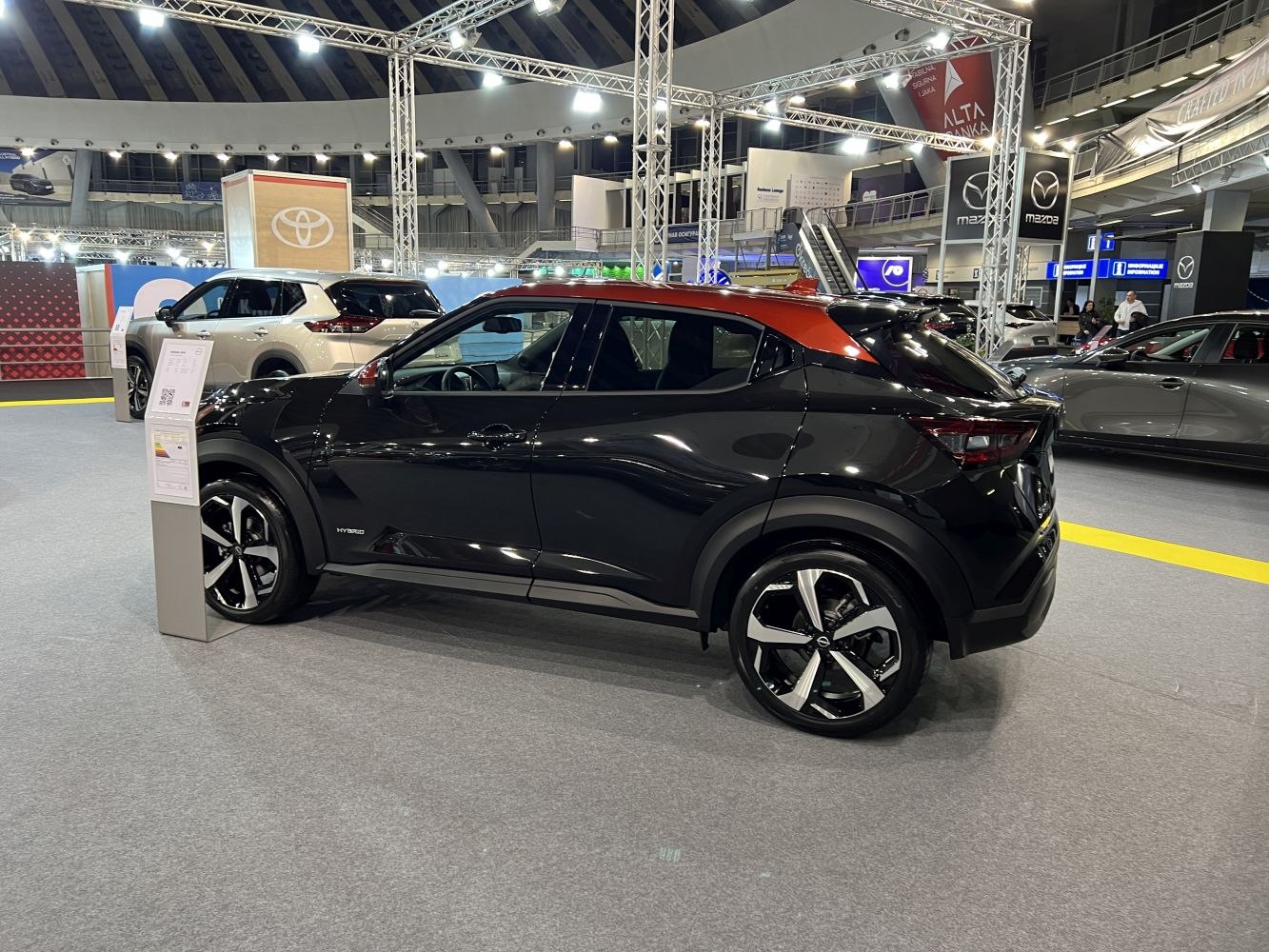 Black compact SUV with orange roof and hybrid badge, side profile view.