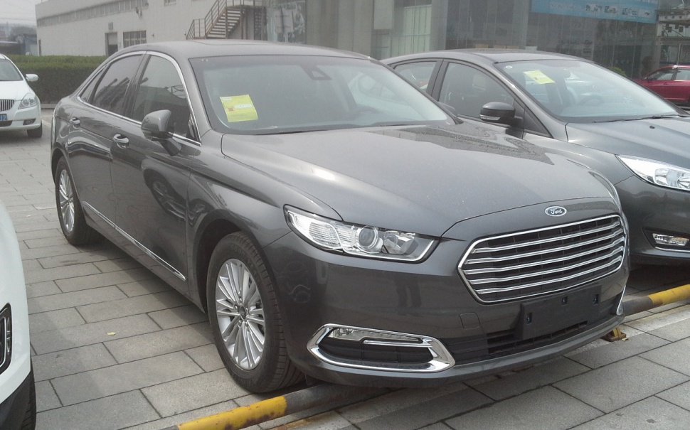 Front-side view of dark gray sedan with signature grille and headlights