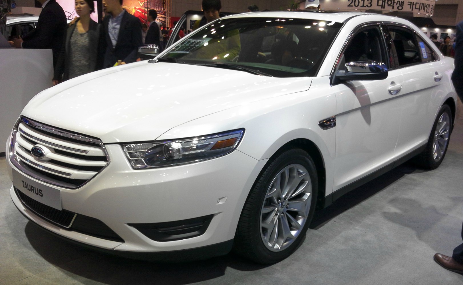 Front grille with sleek headlights and alloy wheels on white sedan