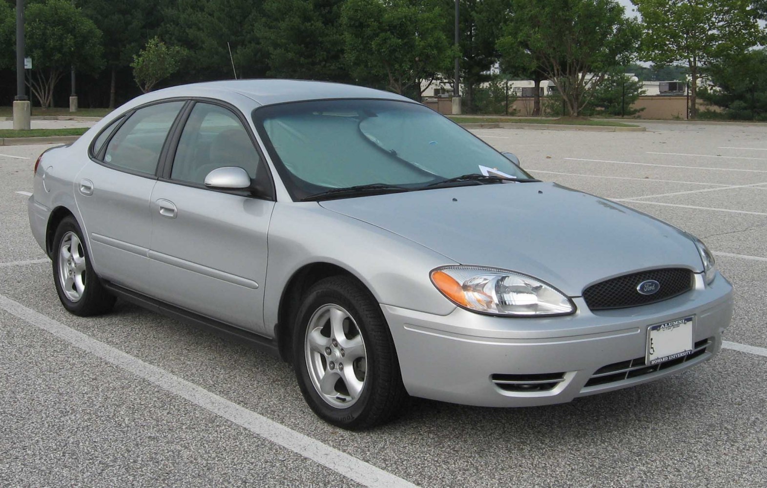 Silver sedan front side with headlights and grille in parking lot