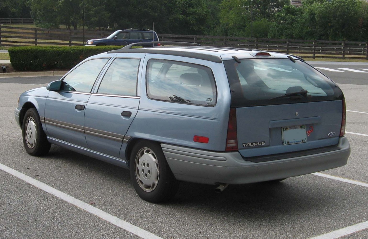 Rear and side view of a 1990s station wagon with boxy design and roof rack