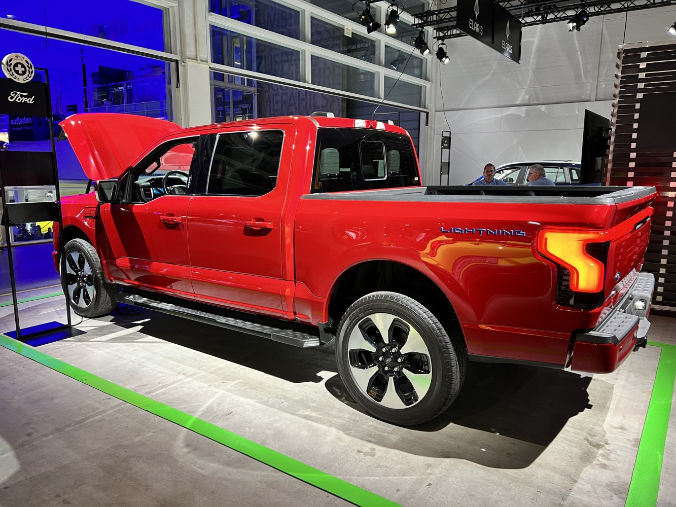 Red electric pickup truck with open hood and rear distinctive lighting