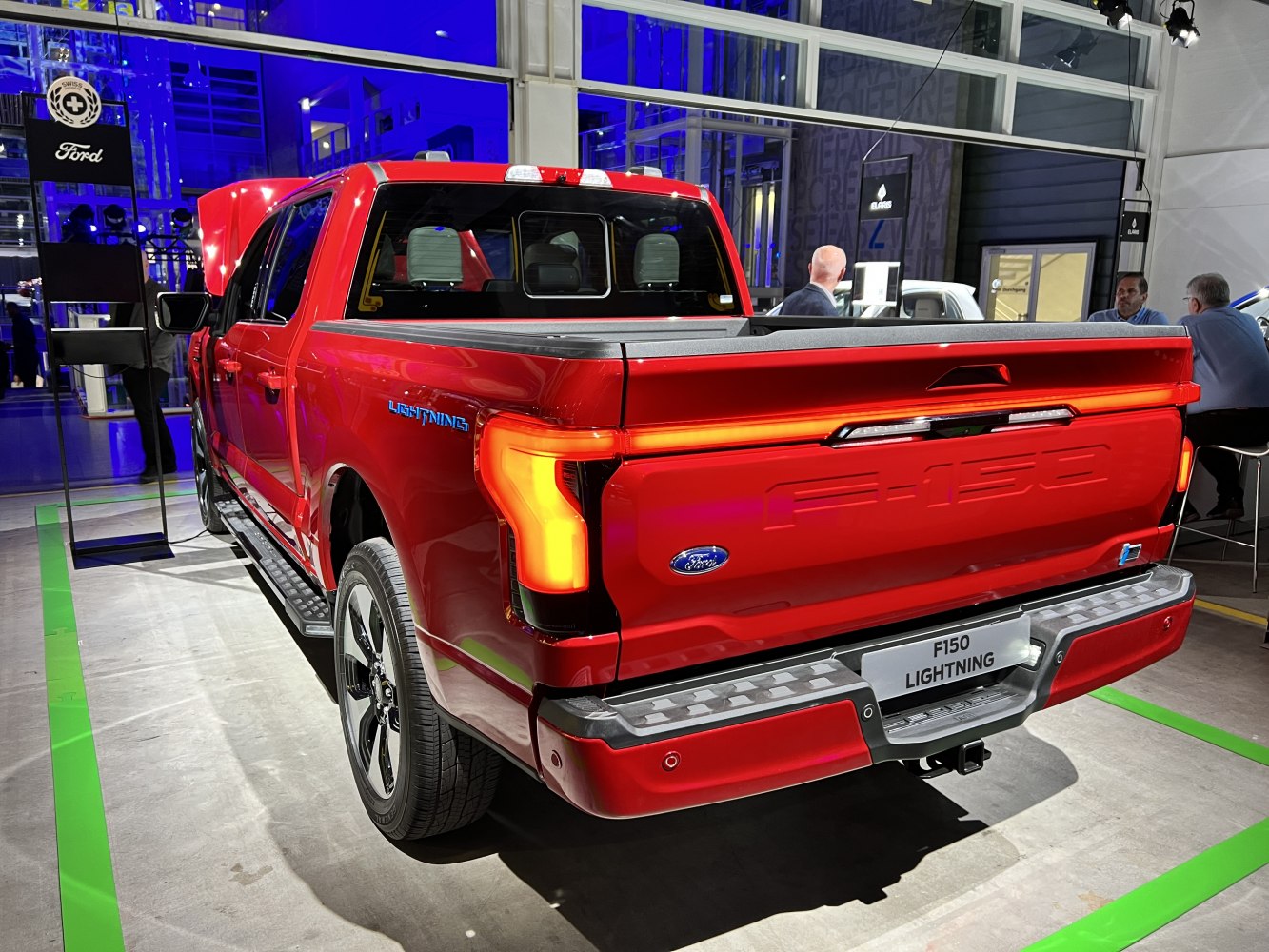 Rear view of red electric pickup with tailgate and illuminated taillights