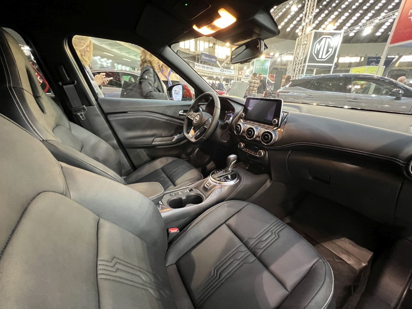 Car interior with digital infotainment, round air vents, and automatic gear shift