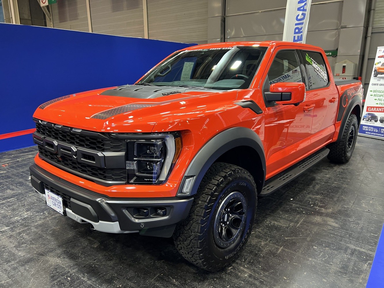 Bold orange pickup with aggressive grille, robust hood, off-road tires.