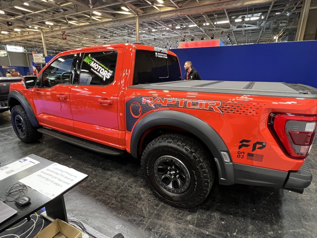 Red pickup with black wheels, aggressive tires, Raptor decal, covered truck bed