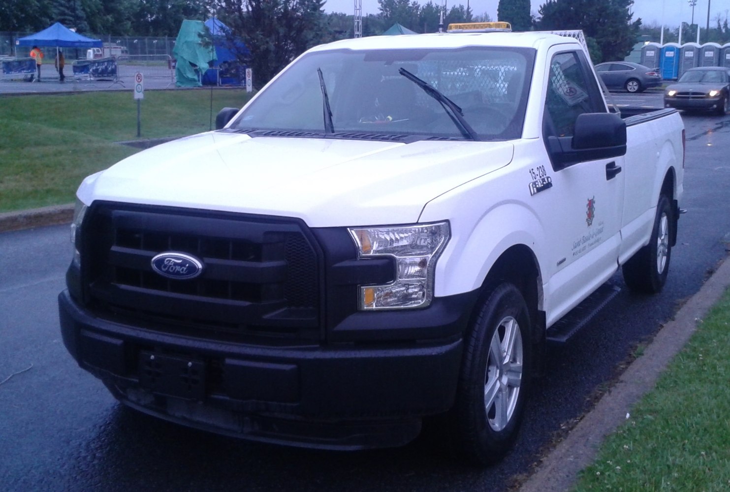 White pickup truck with black grille and bumper, parked on wet road