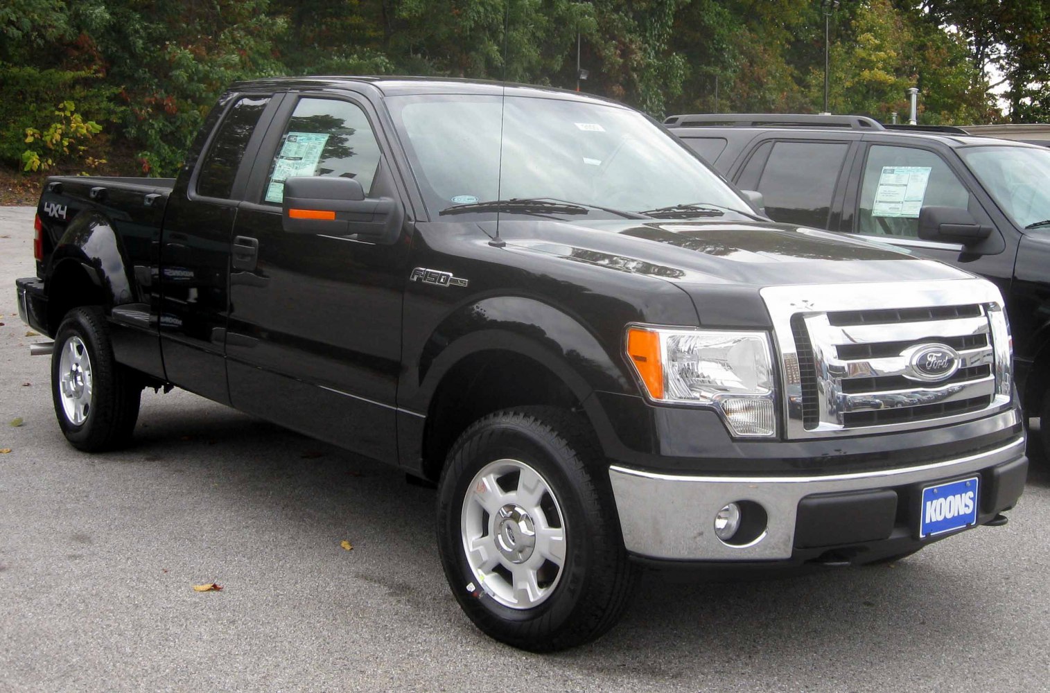 Front-side view of black extended cab pickup truck with chrome grille