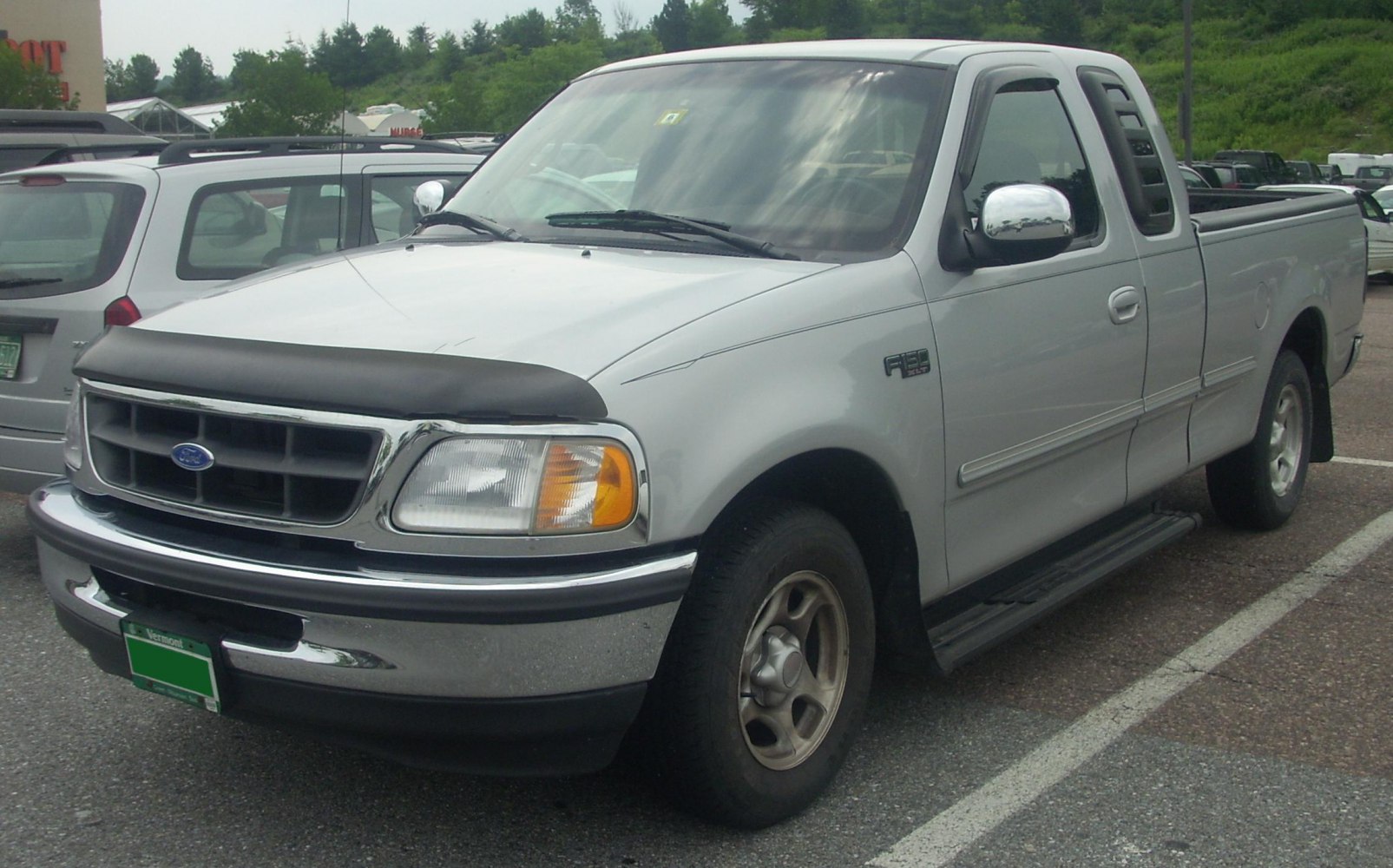 Extended cab pickup truck with chrome bumper and front-side view.