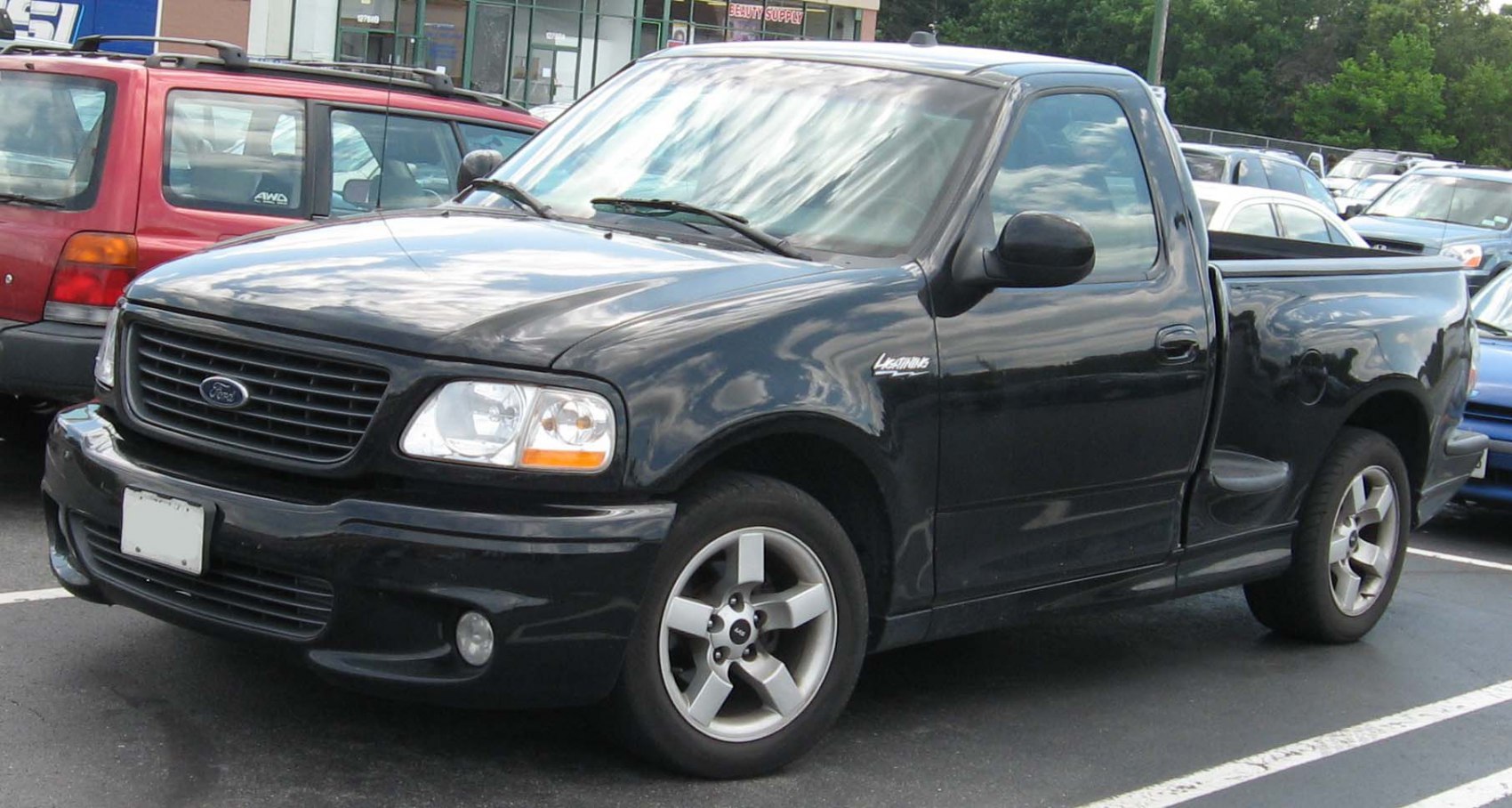 Black regular cab pickup truck front side view with grille and alloy wheels