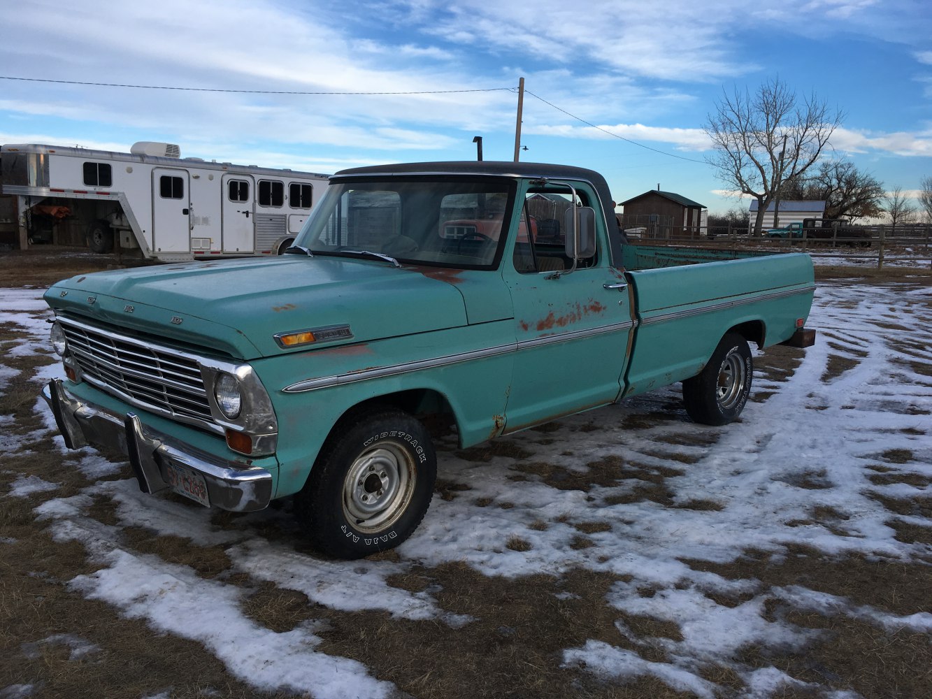 Side-front view of vintage pickup truck with rust and snow