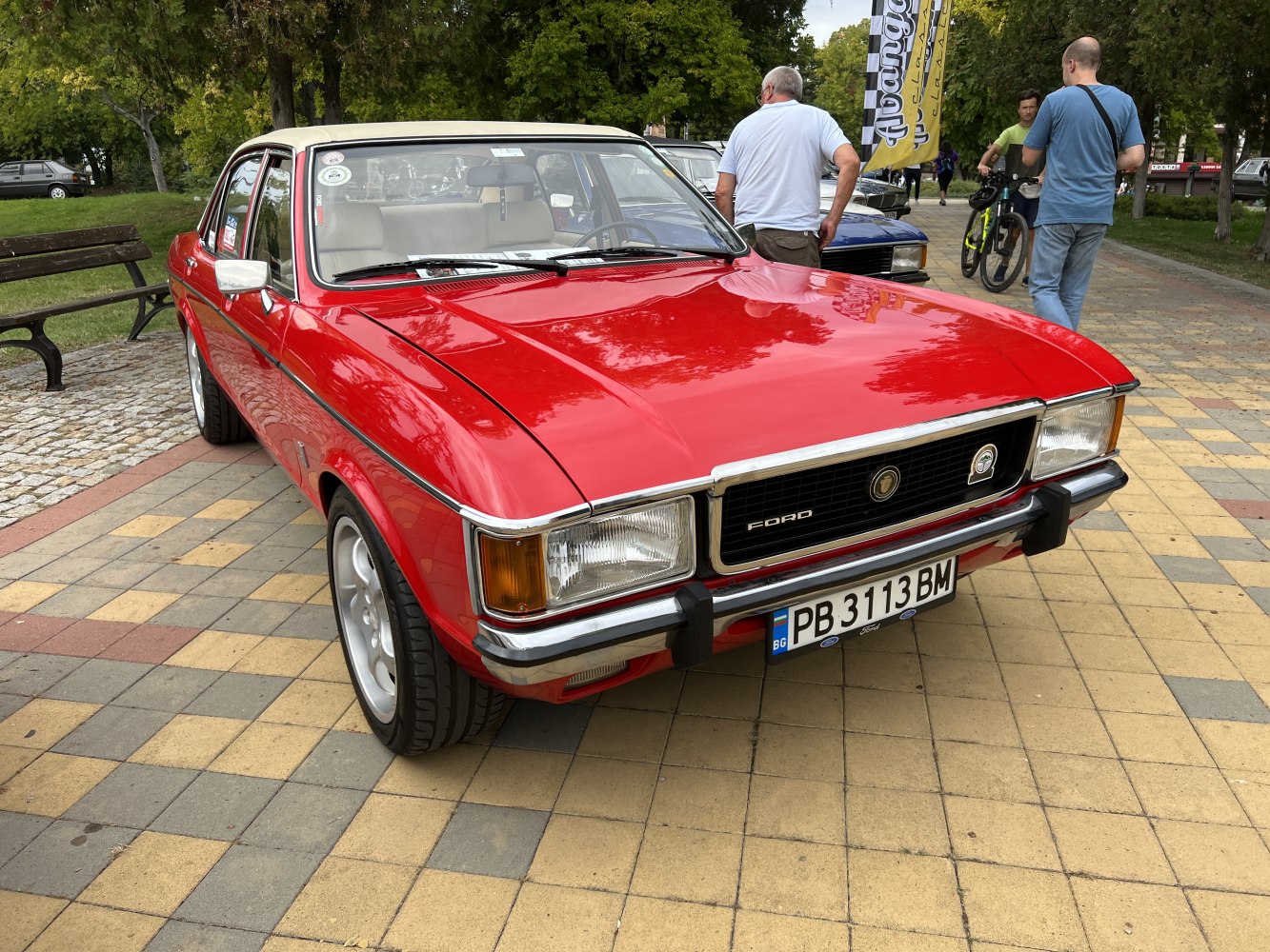 Red sedan with chrome grille and rectangular headlights on tiled pavement
