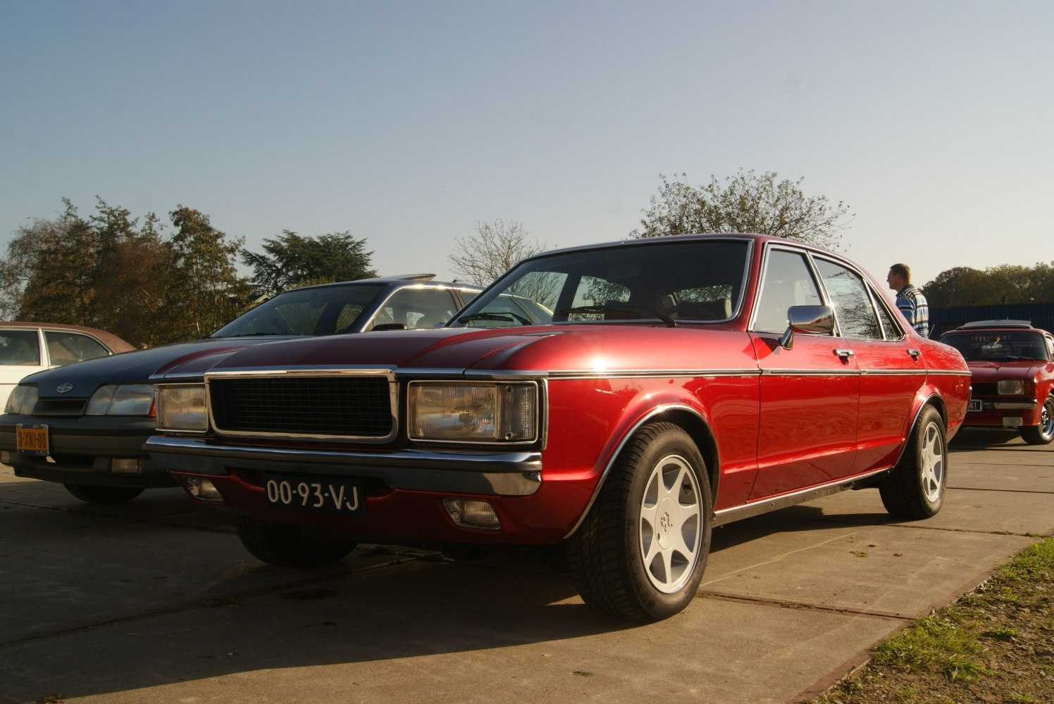 Rectangular headlights and sleek front grille on a vintage sedan in polished red.