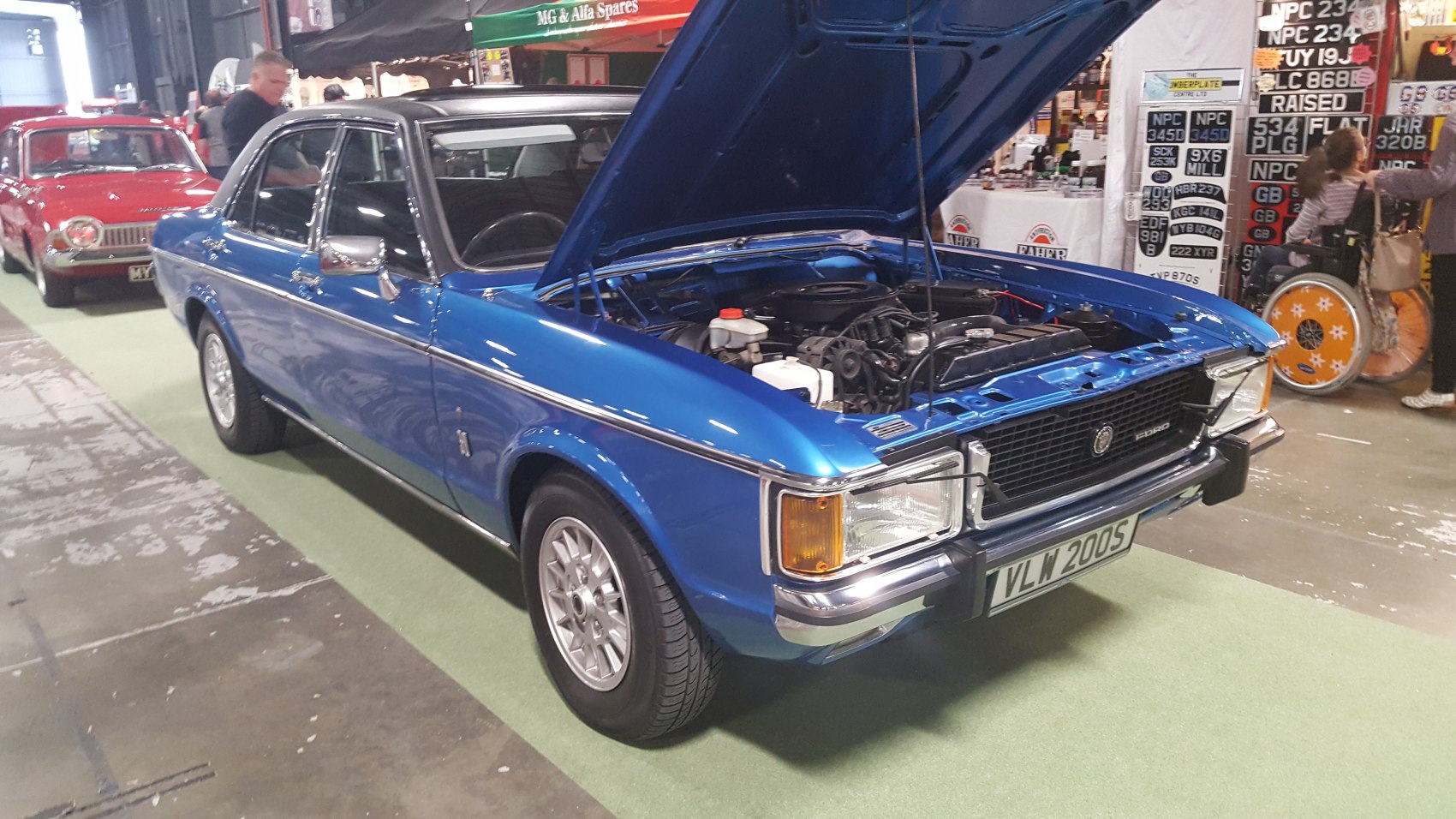 Blue vintage coupe with open engine hood and distinctive front grille
