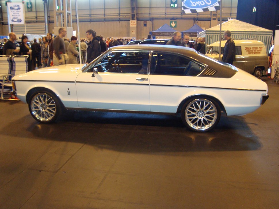 Side profile of a vintage coupe with custom alloy wheels and streamlined design.