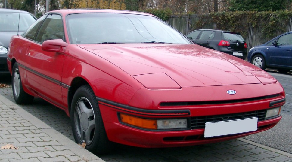 Red coupe front view with pop-up headlights and aerodynamic shape
