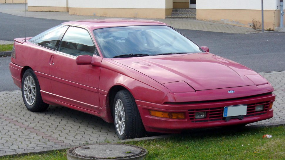 Red sports coupe with pop-up headlights and alloy wheels.